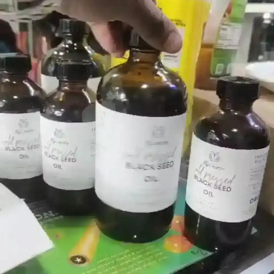 Multiple bottles of black seed oil with white labels displayed on a counter