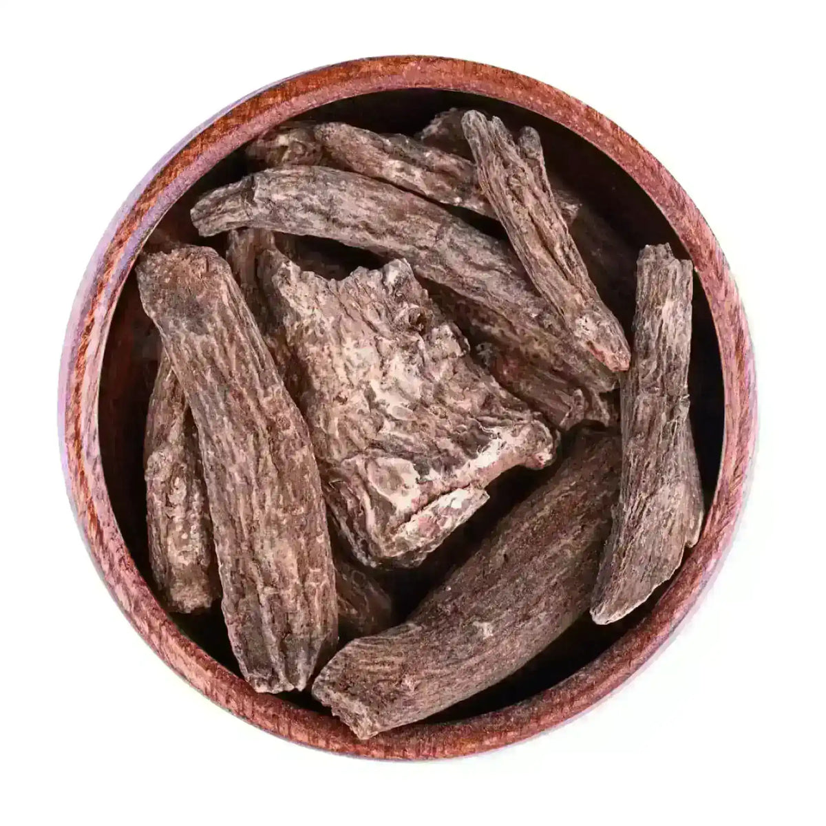 Coarse dried Indian costus roots in a brown wooden bowl on white background