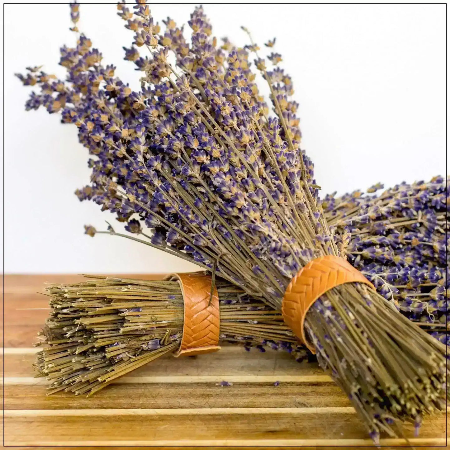 Dried lavender bundles with purple flowers tied with braided bands on a wooden surface
