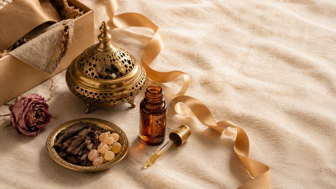 Arabic fragrance gift arrangement with amber perfume oil bottle, brass bakhoor burner, frankincense resin and oud chips with gold silk ribbon