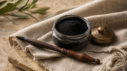 A traditional mirwad applicator beside a small pot of fine black ithmid kohl powder.