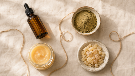Curated Middle Eastern starter kit flat lay with an amber oil bottle, herbal powder, creamy honey and frankincense resin on linen