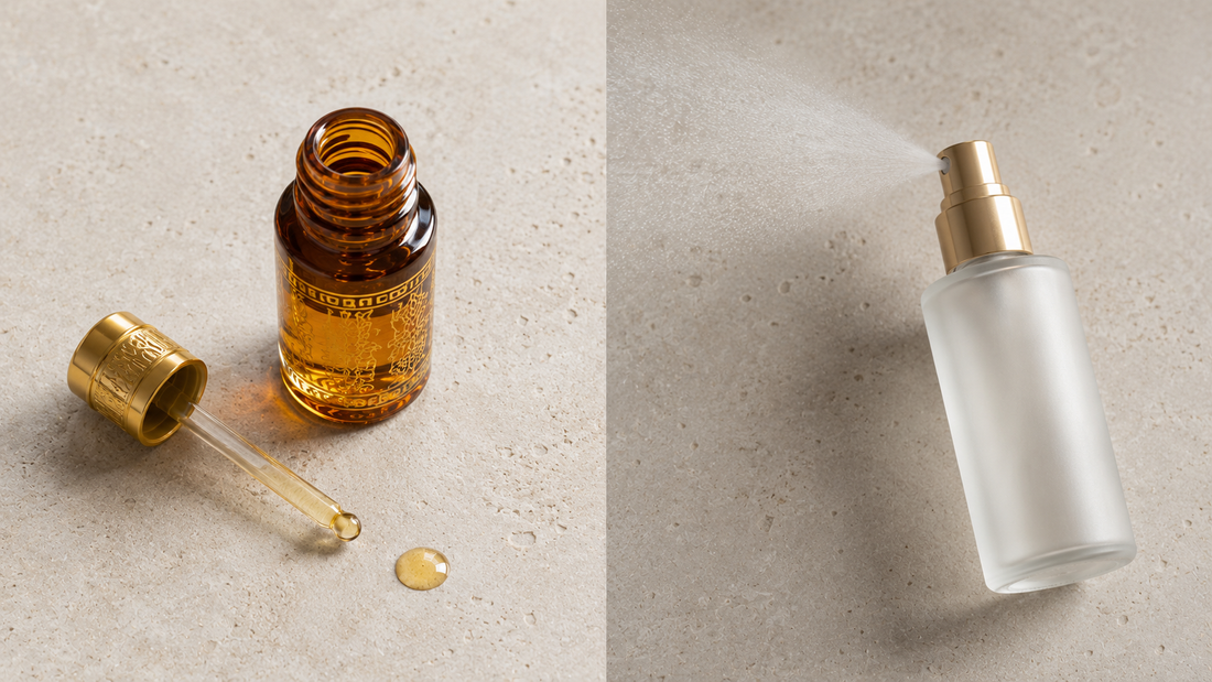 Amber perfume oil bottle with glass applicator and a single oil drop beside a frosted spray bottle releasing fine mist