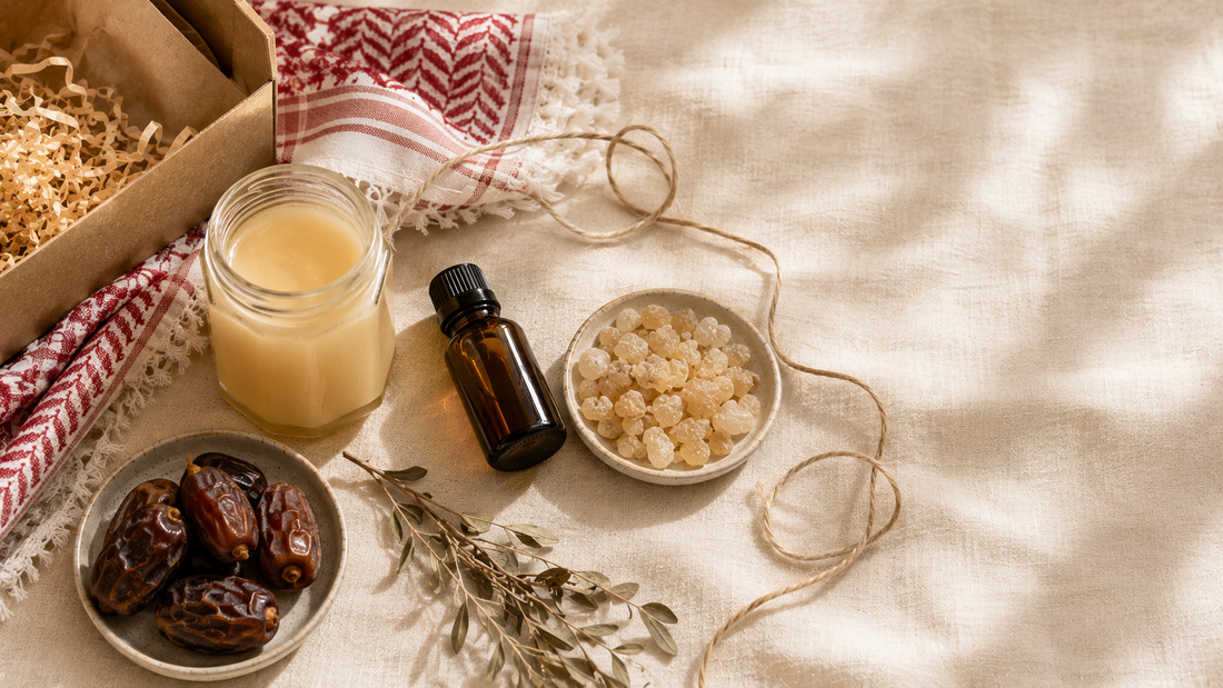 Middle Eastern gift arrangement with creamy honey, frankincense resin, an amber oil bottle, dates and red-patterned textile on linen