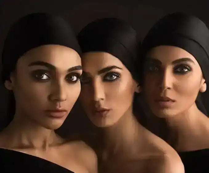 Portrait of three women with dark headscarves and striking smoky eye makeup against a dark background