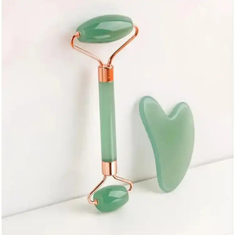 Green jade roller and gua sha facial massage tool set on a white background