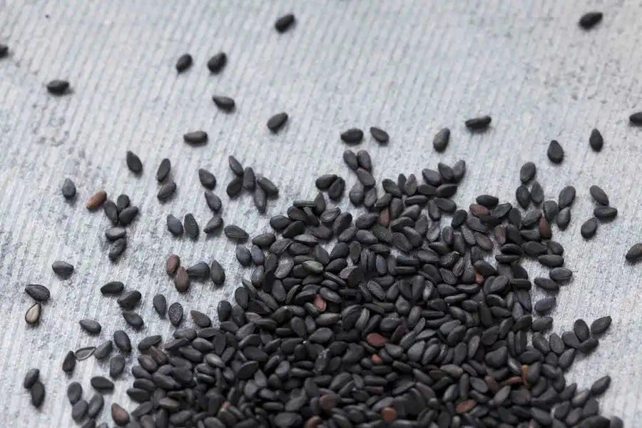Black sesame seeds scattered on textured surface, natural Middle Eastern spice ingredient