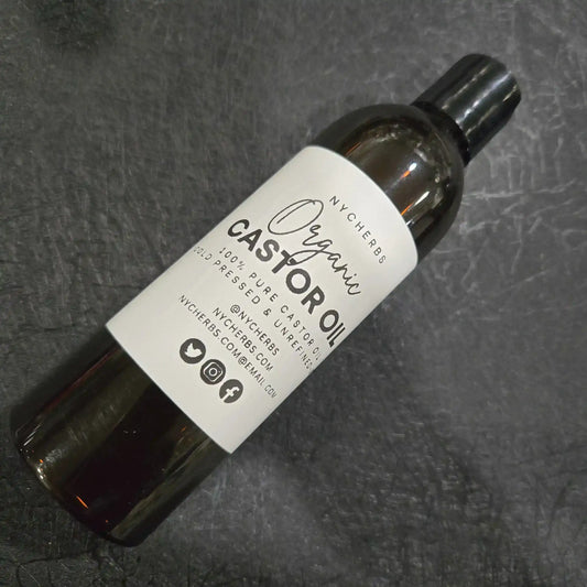 Bottle of organic castor oil with white label on textured black background