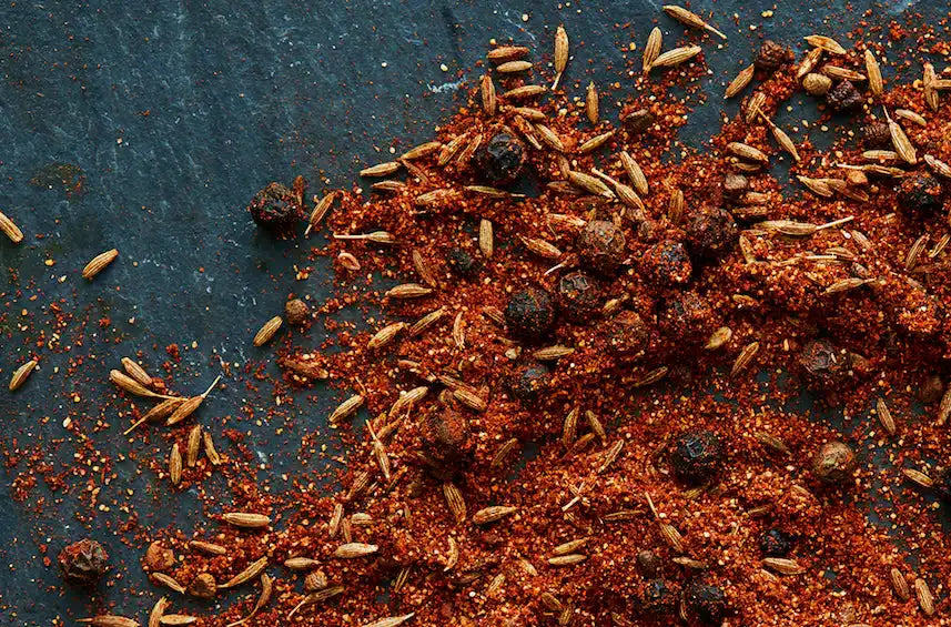 Authentic Middle Eastern spice blend with cumin seeds and peppercorns on dark slate
